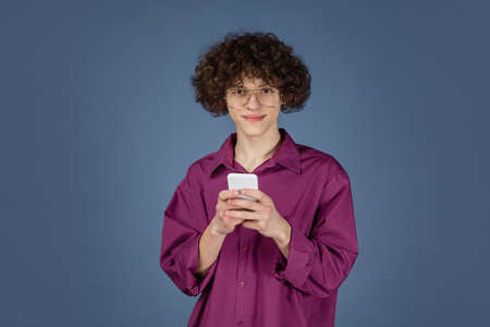 Scrolling. Caucasian young handsome mans portrait on blue studio background with copyspace. Male...