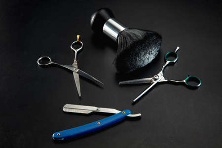 Barber shop equipment set isolated on black table background. Close up sccissors, comb, brushes,...