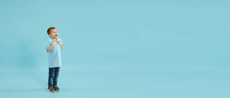 Astonished, flyer. Childhood and dream about big and famous future. Pretty little boy isolated on blue studio background. Dreams, imagination, education, facial expression, emotions concept.の写真素材