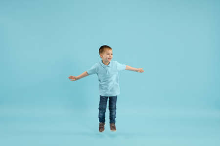 Childhood and dream about big and famous future. Pretty little boy isolated on blue studio background. Dreams, imagination, education, facial expression, emotions concept. Copyspace.の写真素材