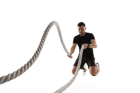 Ropes. Caucasian professional sportsman training isolated on white studio background. Muscular,...