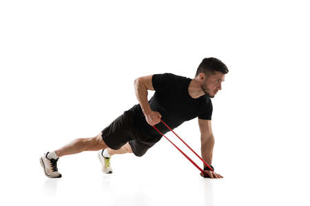 Stretching. Caucasian professional sportsman training isolated on white studio background. Muscular,...
