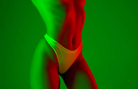 Fashion. Beautiful female belly on green background in neon light. Beauty, cosmetics, spa, depilation, diet and treatment, fitness concept. Fit and sportive, sensual body with well-kept skin.の写真素材