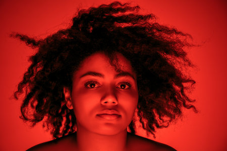 Dancing. Beautiful african-american womans portrait isolated on red studio background in neon,...
