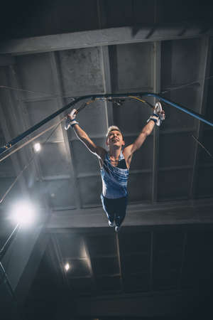 Flying. Little male gymnast training in gym, composed and active. Caucasian fit boy, athlete in sportswear practicing in exercises for strength, balance. Movement, action, motion, dynamic conceptの写真素材