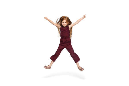 Jumping, running. Happy, smiley little caucasian girl isolated on white studio background with copyspace for ad. Looks happy, cheerful. Childhood, education, human emotions, facial expression concept.の写真素材