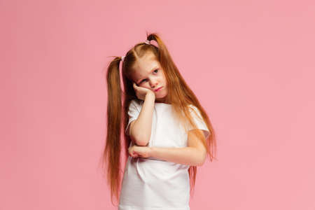Bored, desponded. Happy, smiley little caucasian girl isolated on pink studio background with...