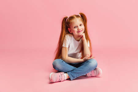 Cute smiling. Happy, smiley little caucasian girl isolated on pink studio background with copyspace for ad. Looks happy, cheerful. Childhood, education, human emotions, facial expression concept.の写真素材