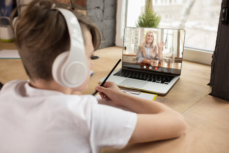 Little boy studying by group video call, use video conference with teacher, listening to online...
