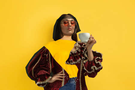 Woman drinking coffee. Magazine style collage with model outfit mixed of different eras. Copyspace for ad. Trendy colors, modern and vintage, renaissansse fashion. Cintemporary art collage.の写真素材