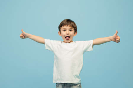 Thumbs up. Happy, smiley little caucasian boy isolated on blue studio background with copyspace for...