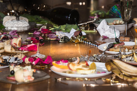 Early morning after the party. Glasses and plates on the table with confetti and serpentine,...