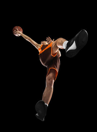 Young professional basketball player in action, motion isolated on black background, look from the bottom. Concept of sport, movement, energy and dynamic.の写真素材