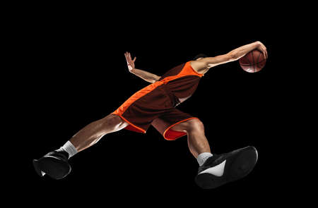 Young professional basketball player in action, motion isolated on black background, look from the bottom. Concept of sport, movement, energy and dynamic.の写真素材