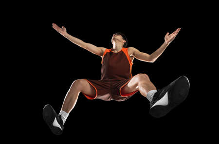 Young professional basketball player in action, motion isolated on black background, look from the bottom. Concept of sport, movement, energy and dynamic.の写真素材