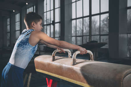 Little male gymnast training in gym, flexible and active. Caucasian fit little boy, athlete in sportswear practicing in exercises for strength, balance.の写真素材