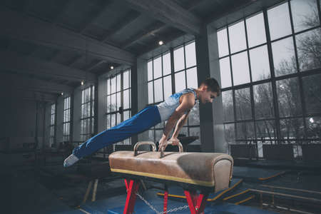 Little male gymnast training in gym, flexible and active. Caucasian fit little boy, athlete in sportswear practicing in exercises for strength, balance.の写真素材