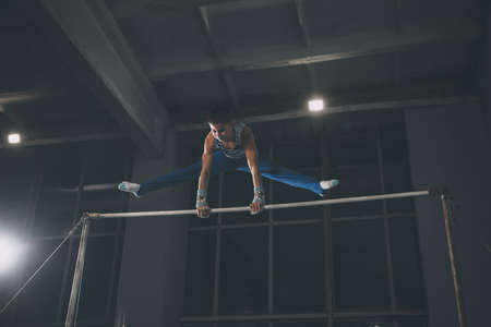 Little male gymnast training in gym, flexible and active. Caucasian fit little boy, athlete in sportswear practicing in exercises for strength, balance.の写真素材