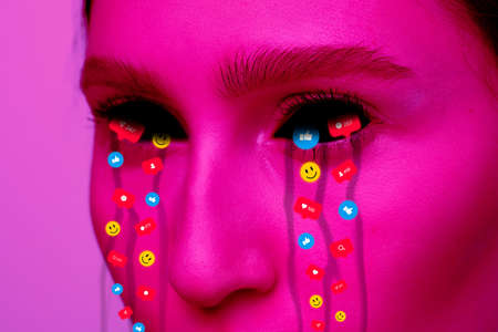 Tears illustrated of social media activity signs on female face in neon light. Real life versus online lifestyle, addiction to modern technologiesの写真素材
