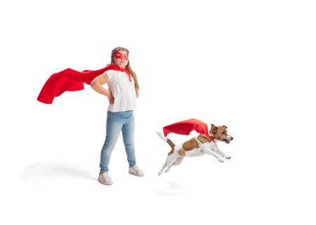 Child pretending to be a superhero with her super dog isolated on white studio backgroundの写真素材