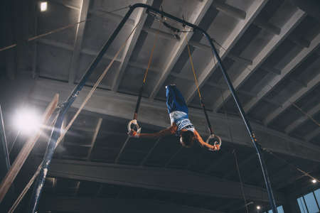 Little male gymnast training in gym, flexible and active. Caucasian fit little boy, athlete in sportswear practicing in exercises for strength, balance.の写真素材