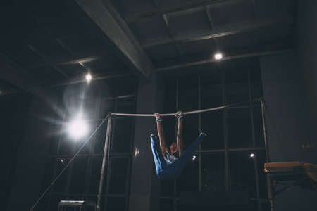 Little male gymnast training in gym, flexible and active. Caucasian fit little boy, athlete in sportswear practicing in exercises for strength, balance.の写真素材
