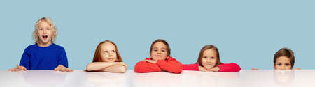 Little and happy kids gesturing isolated on blue studio background. Human emotions, facial expression conceptの写真素材