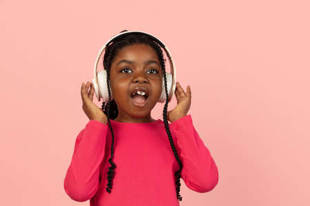 Handsome african little girl portrait isolated on pink studio background with copyspaceの写真素材