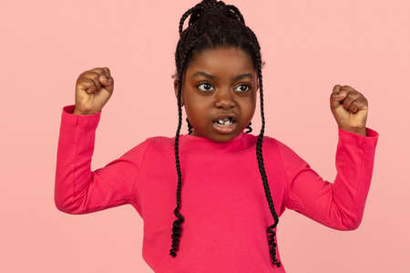 Handsome african little girl portrait isolated on pink studio background with copyspaceの写真素材