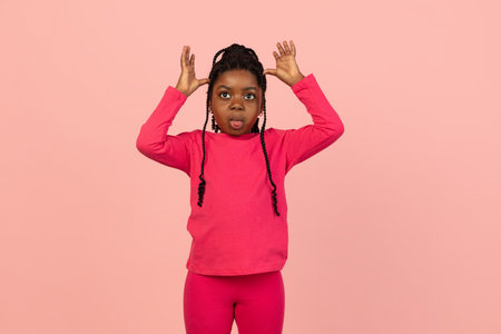 Handsome african little girl portrait isolated on pink studio background with copyspaceの写真素材