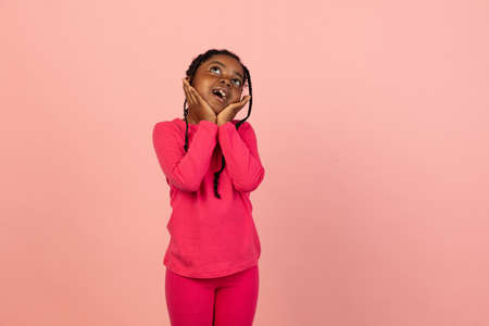 Handsome african little girl portrait isolated on pink studio background with copyspaceの写真素材