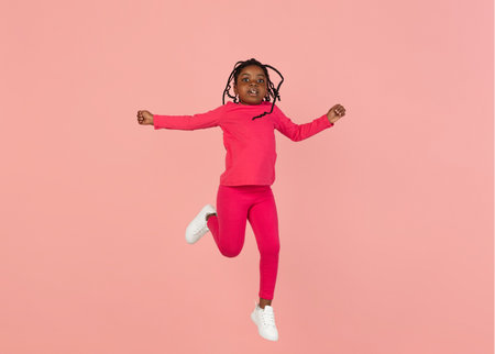 Handsome african little girl portrait isolated on pink studio background with copyspaceの写真素材