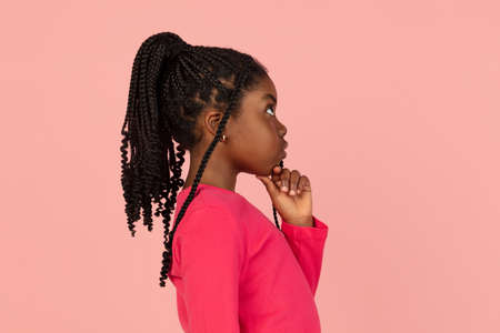 Handsome african little girl portrait isolated on pink studio background with copyspaceの写真素材