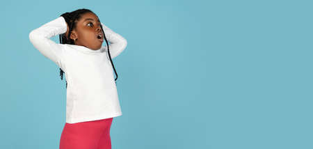 Handsome african little girl portrait isolated on blue studio background with copyspaceの写真素材