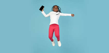 Handsome african little girl portrait isolated on blue studio background with copyspaceの写真素材