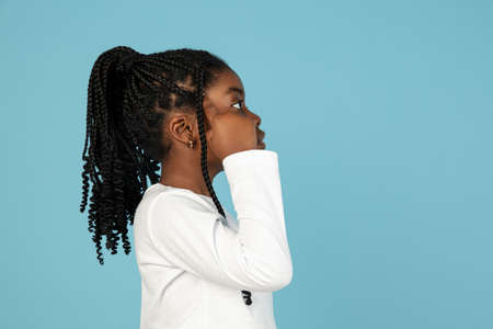 Handsome african little girl portrait isolated on blue studio background with copyspaceの写真素材