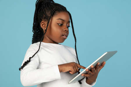 Handsome african little girl portrait isolated on blue studio background with copyspaceの写真素材
