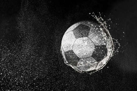 Football, soccer ball flying in water drops and splashes isolated on black backgroundの写真素材