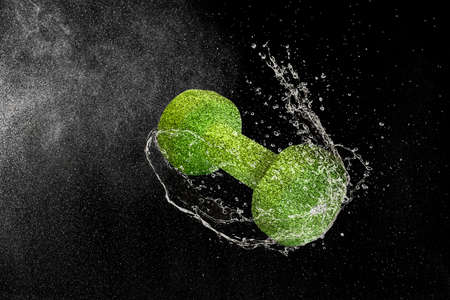 Dumbbell flying in water drops and splashes isolated on black backgroundの写真素材