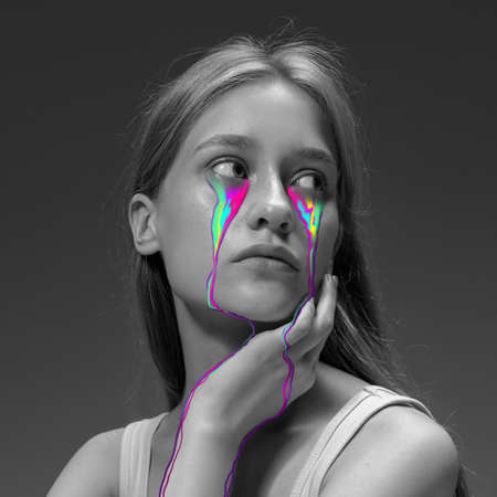 Portrait of young beautiful woman with neon, fluid tears from eyes. Concept of fashion and beauty, emotions and feelings, modern designの写真素材