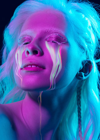 Portrait of young beautiful woman with neon, fluid tears from eyes. Concept of fashion and beauty,...