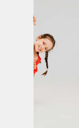 Happy kid, girl isolated on white studio background. Looks happy, cheerful, sincere. Copyspace. Childhood, education, emotions conceptの写真素材