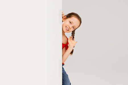 Happy kid, girl isolated on white studio background. Looks happy, cheerful, sincere. Copyspace. Childhood, education, emotions conceptの写真素材