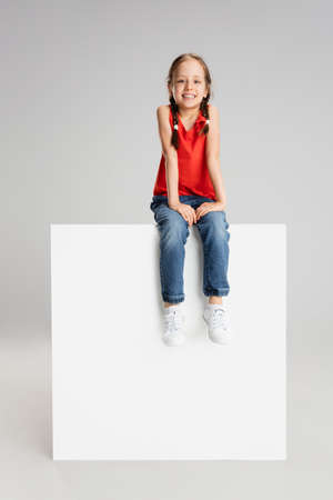 Happy kid, girl isolated on white studio background. Looks happy, cheerful, sincere. Copyspace. Childhood, education, emotions conceptの写真素材