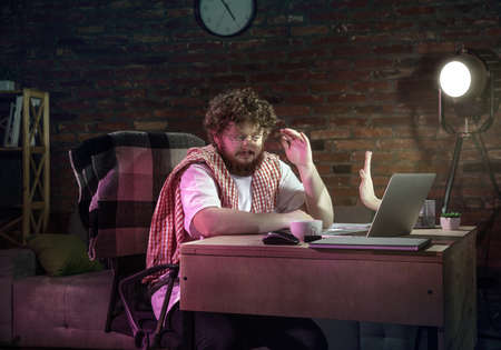 Young Caucasian man talking with friend online through laptop.