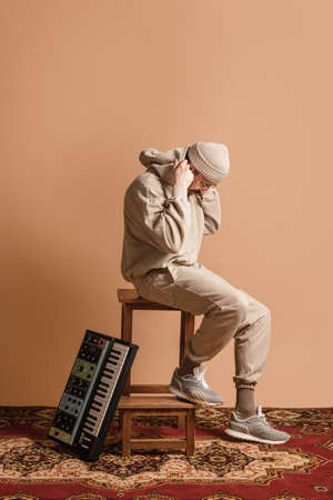Full-length portrait of man, musician isolated on light yellow background.