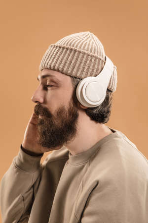 Portrait of Caucasian man in headphones and hat isolated on light background.の写真素材
