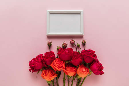 Flowers and white frame on coral pink background. Greeting card to Mother's, Parent's day. Beautiful...