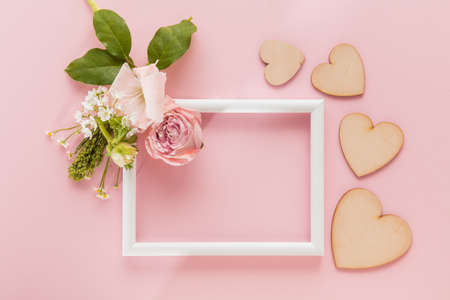 Flowers on white frame on coral pink background. Greeting card to Mother's, Parent's day. Beautiful floral mock up with copyspace. Celebrating, spring and summer mood, family concept. Feminine look.の写真素材