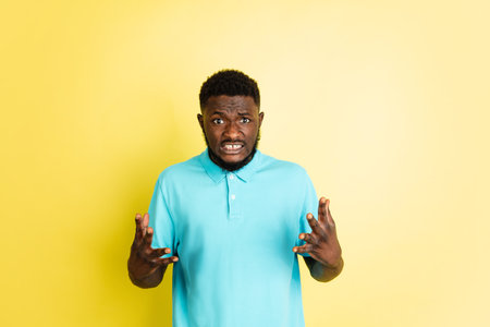 Portrait of young African man isolated over yellow studio background with copyspace.